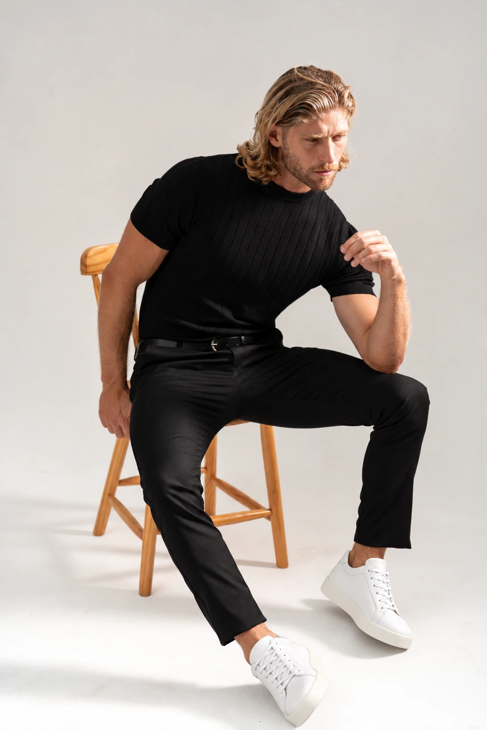 Homem com camiseta preta, calça preta e tênis branco