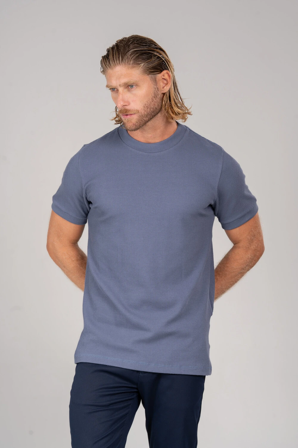 Homem com camiseta texturizada azul-acinzentada e calça azul-marinho