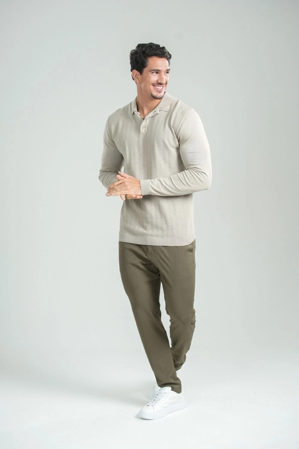Homem com camisa de tricô clara, calça de alfaiataria verde-oliva e tênis branco