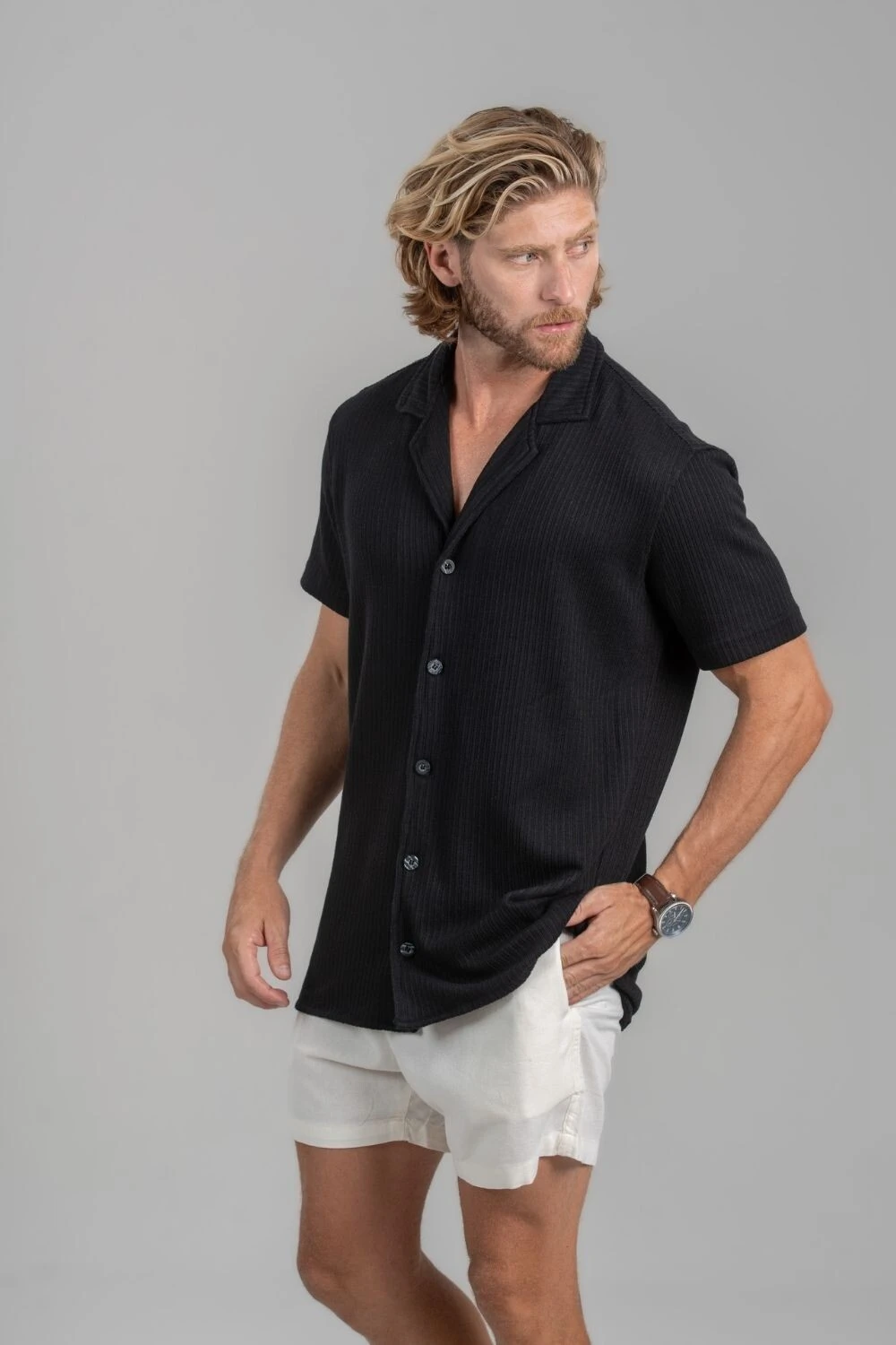 Homem com camisa preta de gola cubana e short off-white