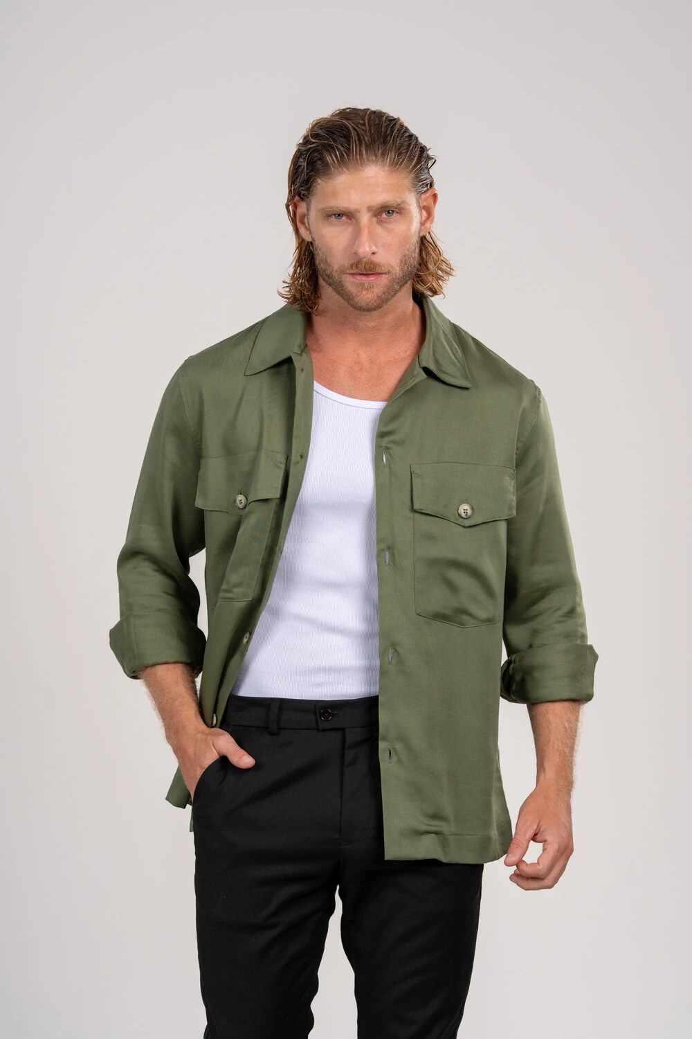 Homem com overshirt verde, regata branca e calça preta