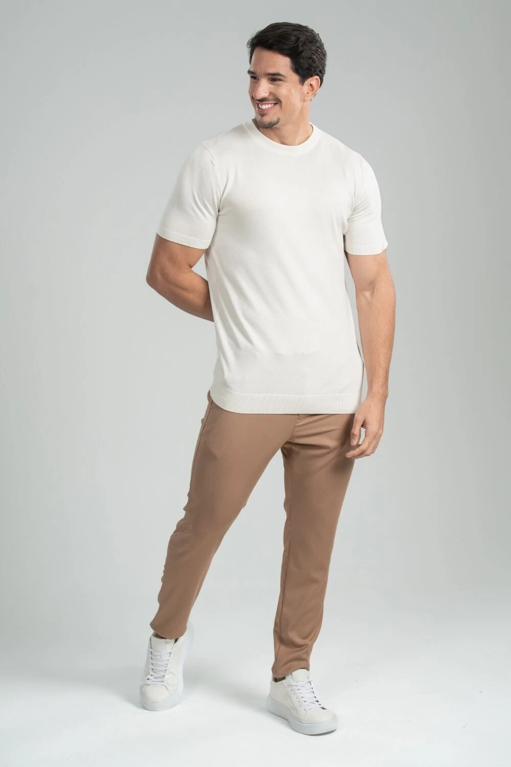 Homem com camiseta off-white, calça de alfaiataria caqui e tênis branco