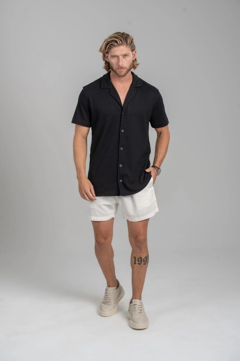 Homem com camisa preta de manga curta e short off-white
