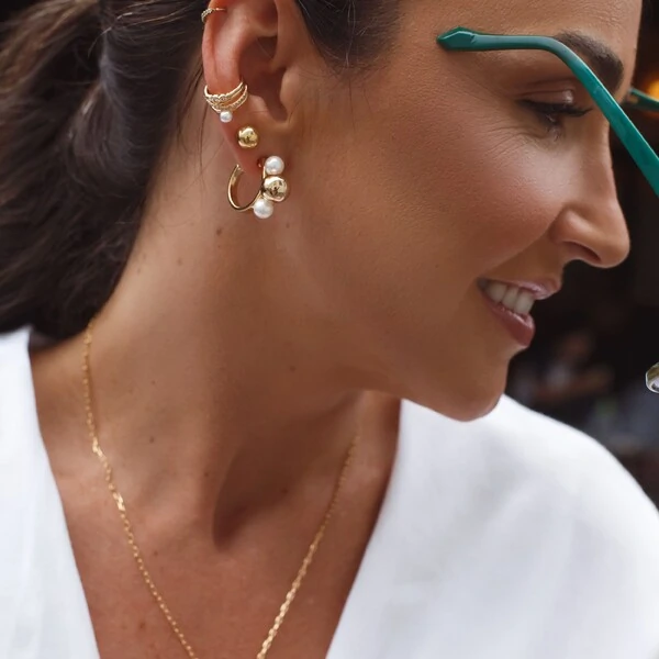 Piercing dourado com pérola shell, colunas com zircônia e folhas curvas