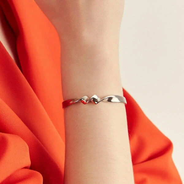 Pulseira bracelete dourado liso com design torcido e curva suave