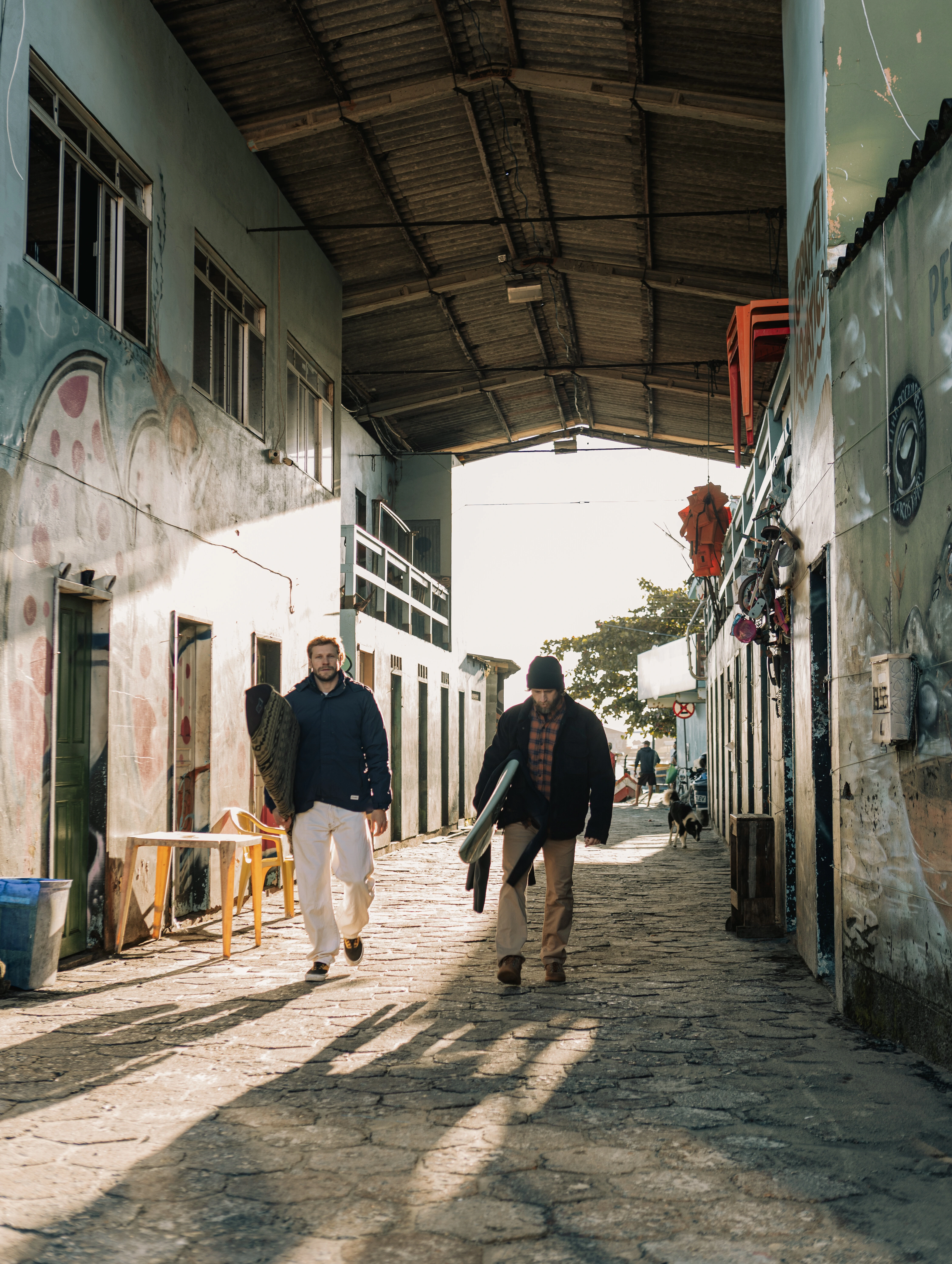 Amigos caminhando com pranchas em vila costeira