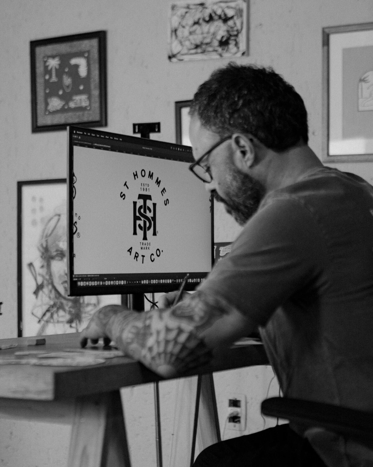 Fabio Luiz em frente ao computador, com o monograma ST da St Hommes na tela, em foto preto e branco