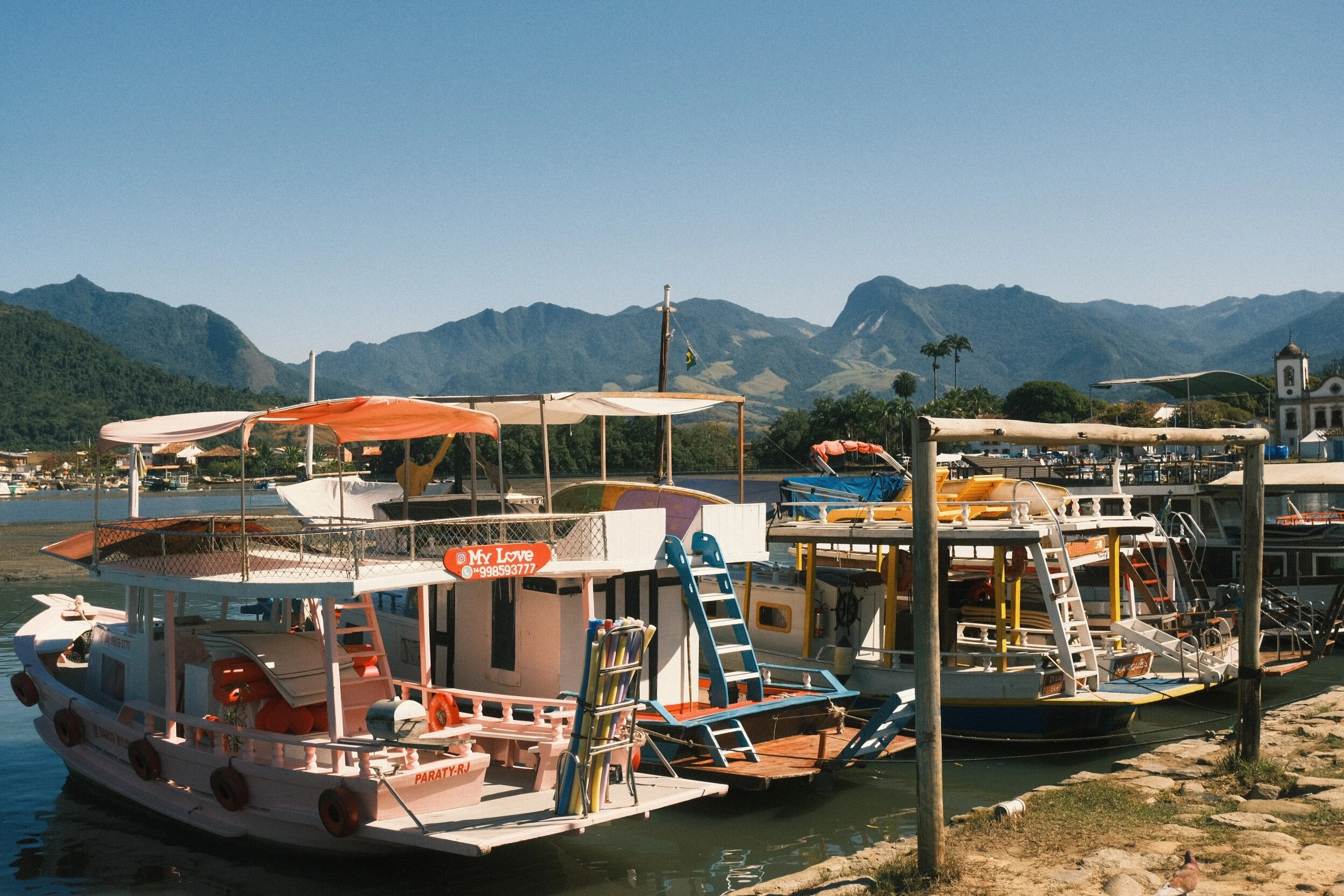 Barcos coloridos no cais de Paraty com as montanhas ao fundo