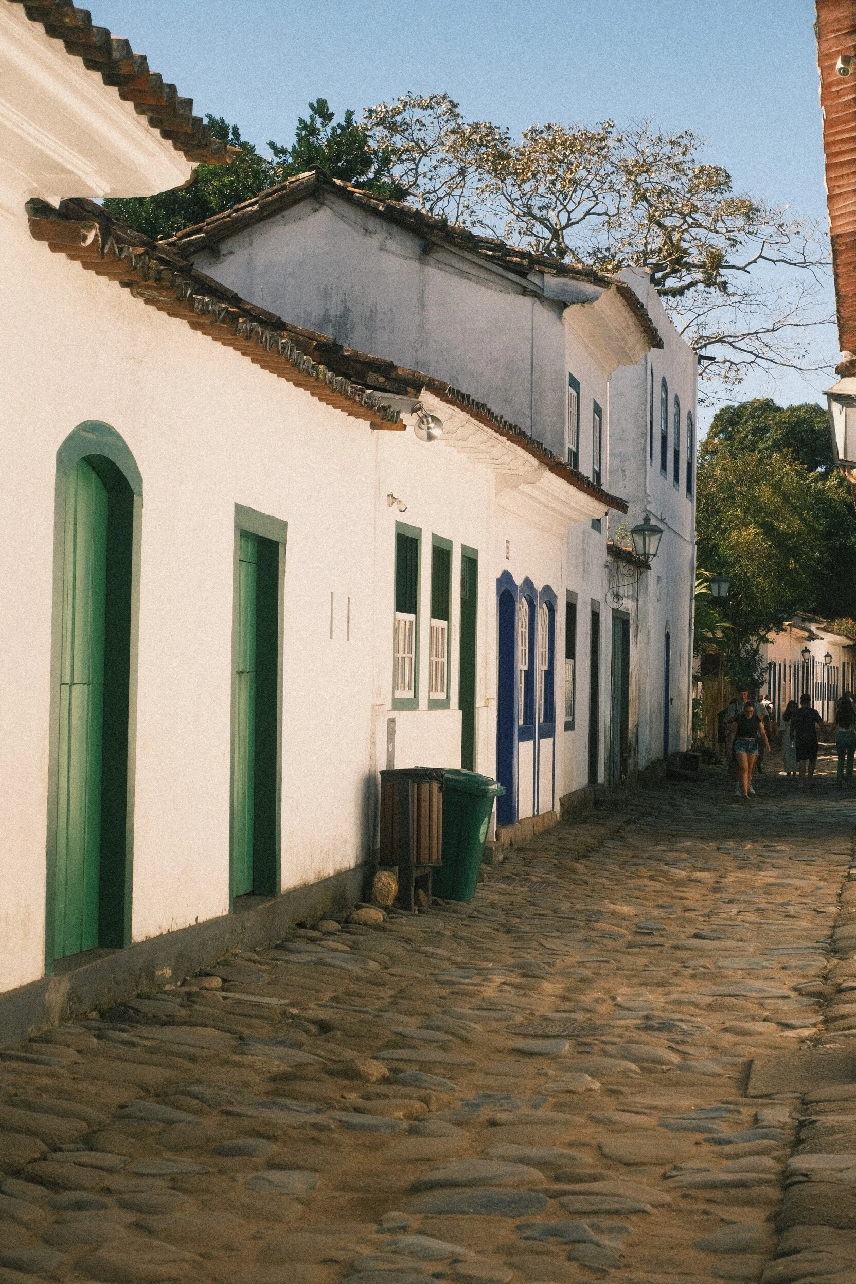 Rua histórica de Paraty com fachadas brancas, portas coloridas e piso de pedra