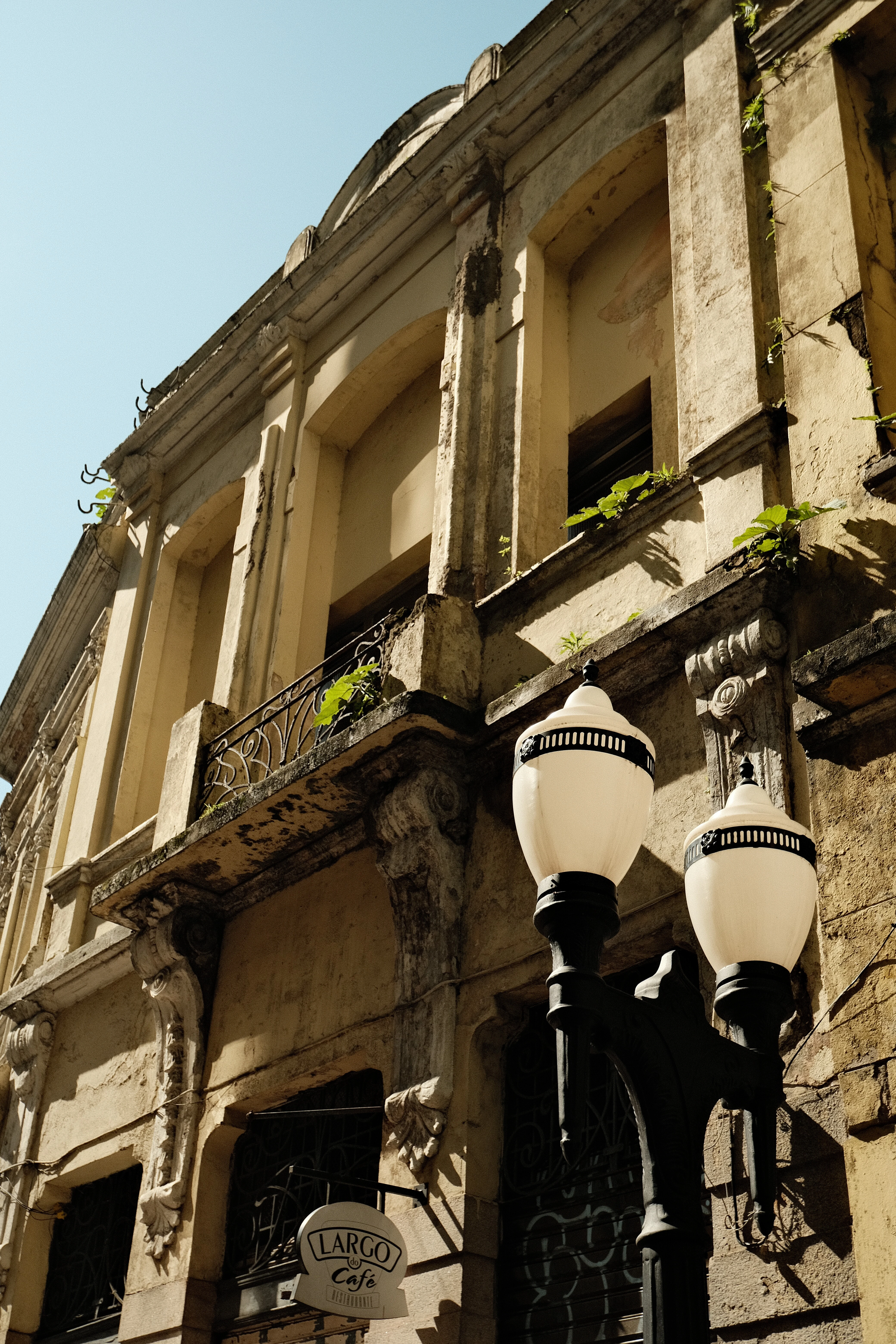 Fachada histórica do centro portuário com sacada de ferro e vegetação natural