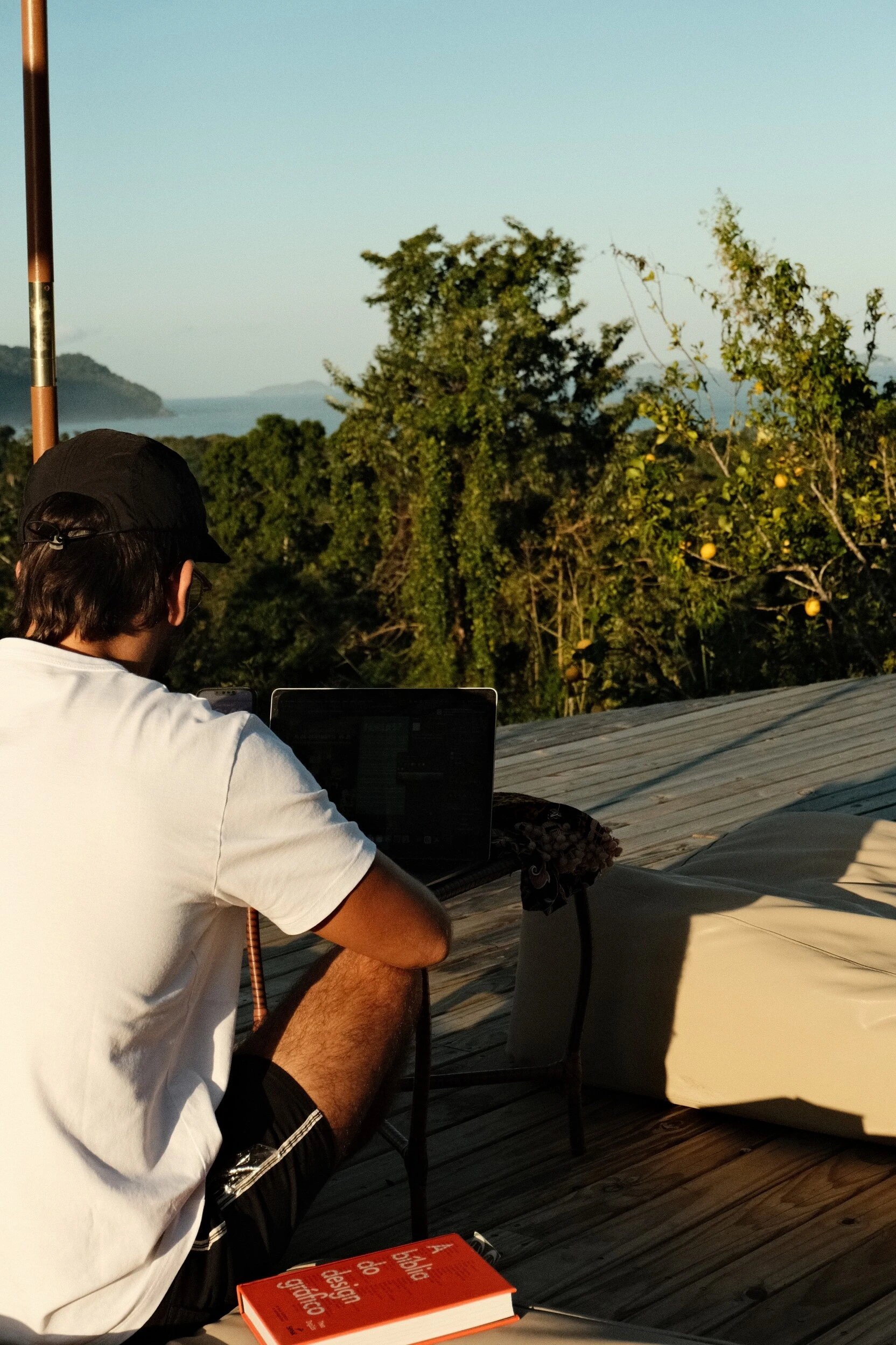 Murilo Lopes sentado no deck da pousada, com o mar e a mata ao fundo