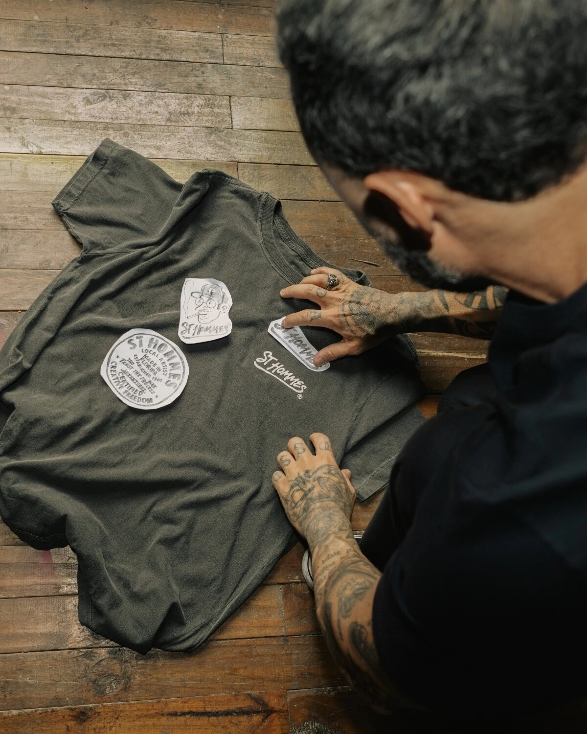 Fabio Luiz posicionando os desenhos recortados sobre uma camiseta escura