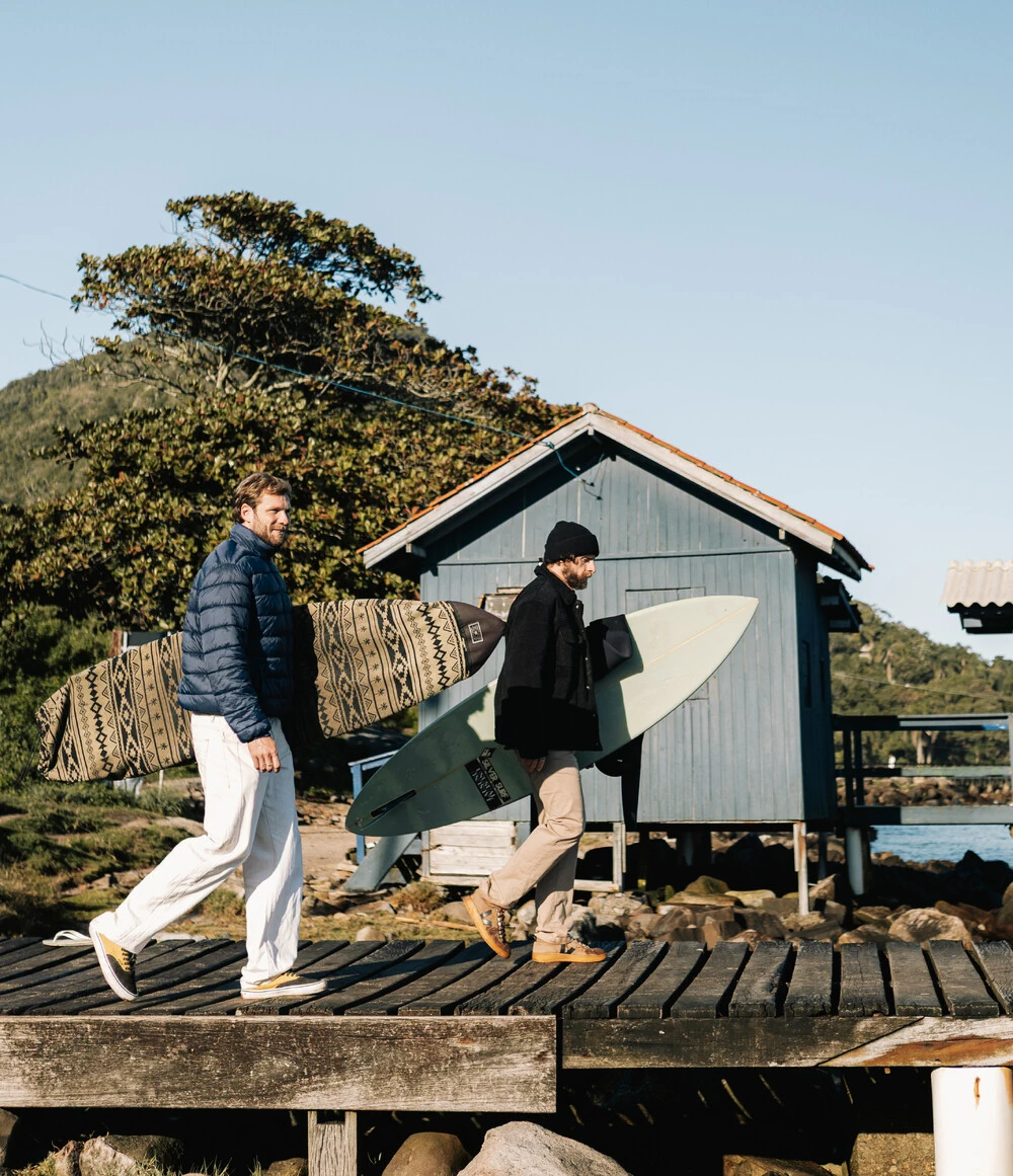 Amigos caminhando com pranchas na costa